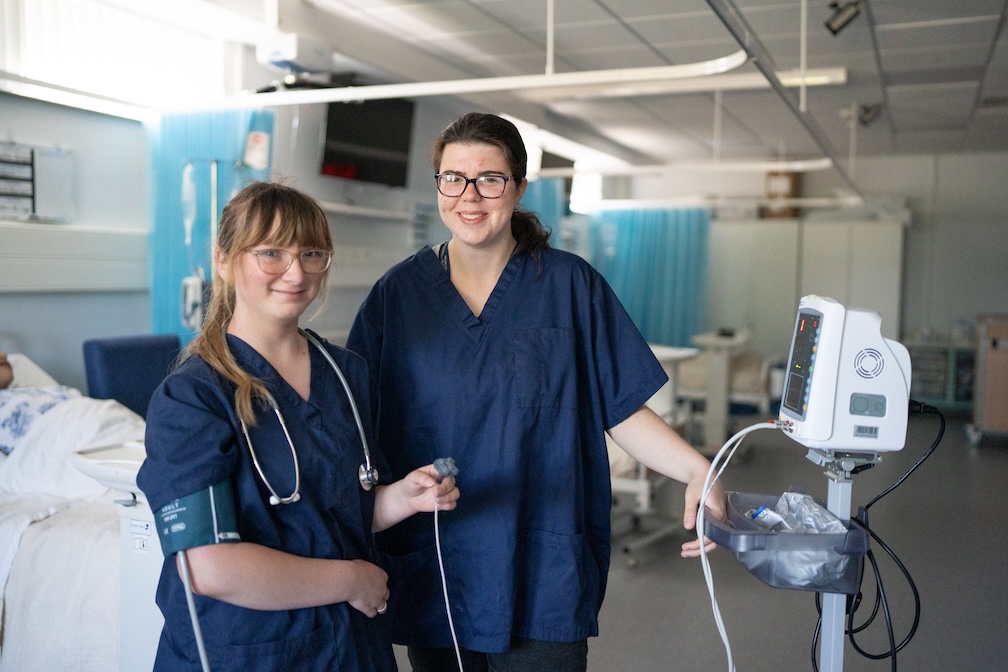 two health students in nurse gear smiling