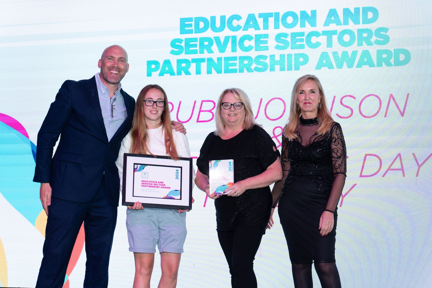 Ruby, standing on stage with her employer, Jaqui Ford and Joe Simms accepting her award