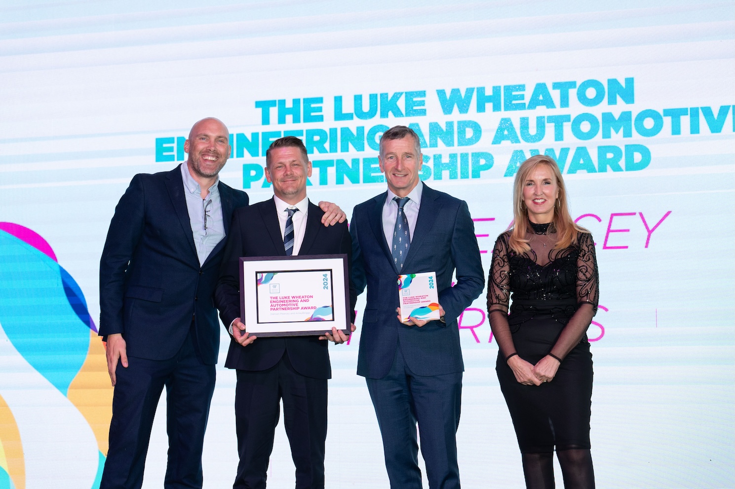 Damien, standing on stage with his employer, Jaqui Ford and Joe Simms accepting his award