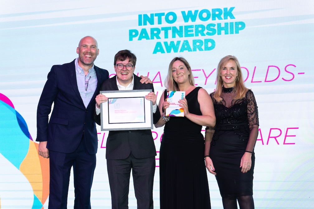 Joshua, standing on stage with his employer, Jaqui Ford and Joe Simms accepting his award