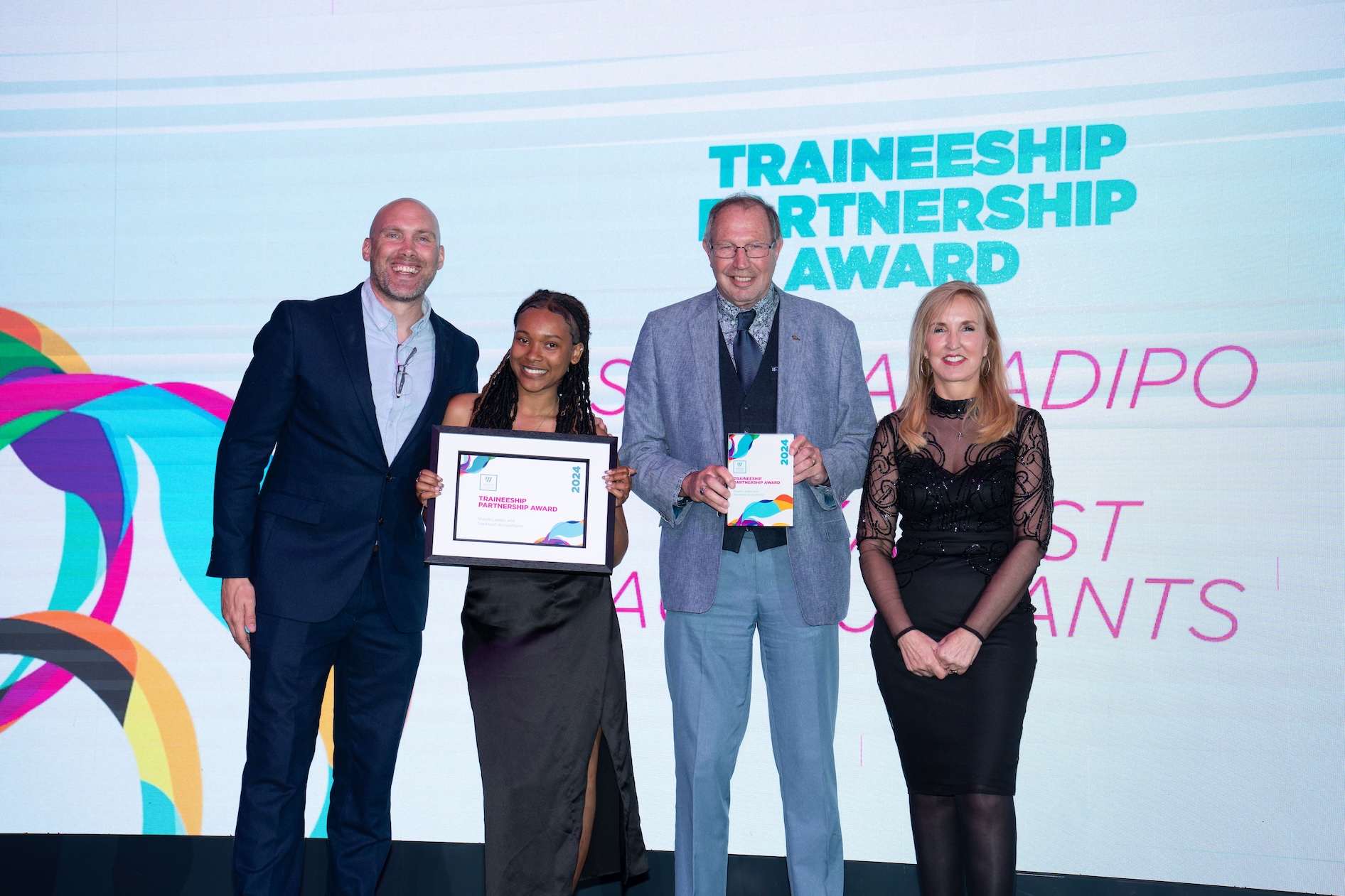 Shayla, standing on stage with her employer, Jaqui Ford and Joe Simms accepting her award