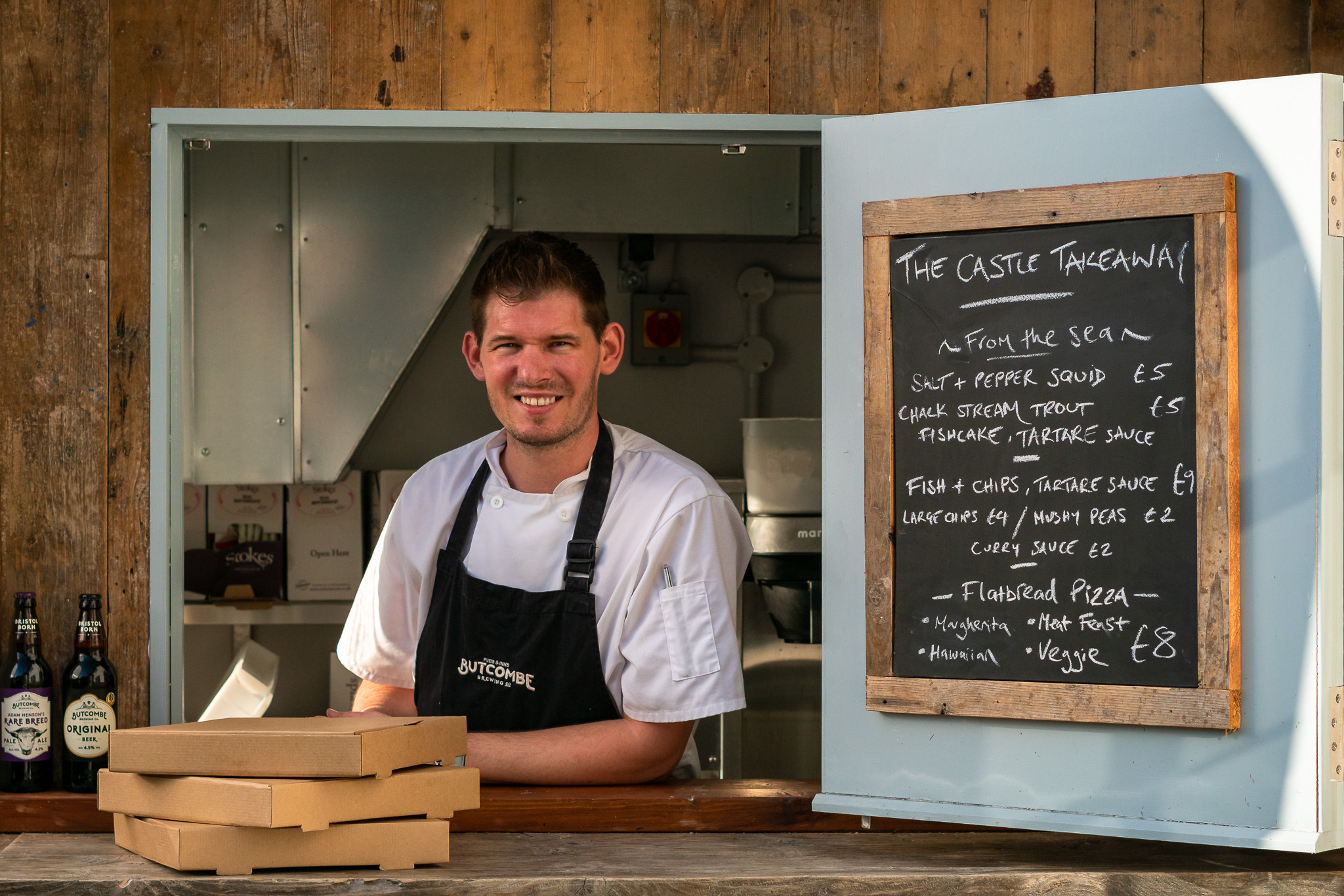 a happy man smiling through the hatch of a food stall