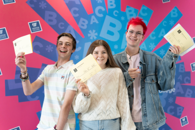 Three of our learners holding their results up proudly