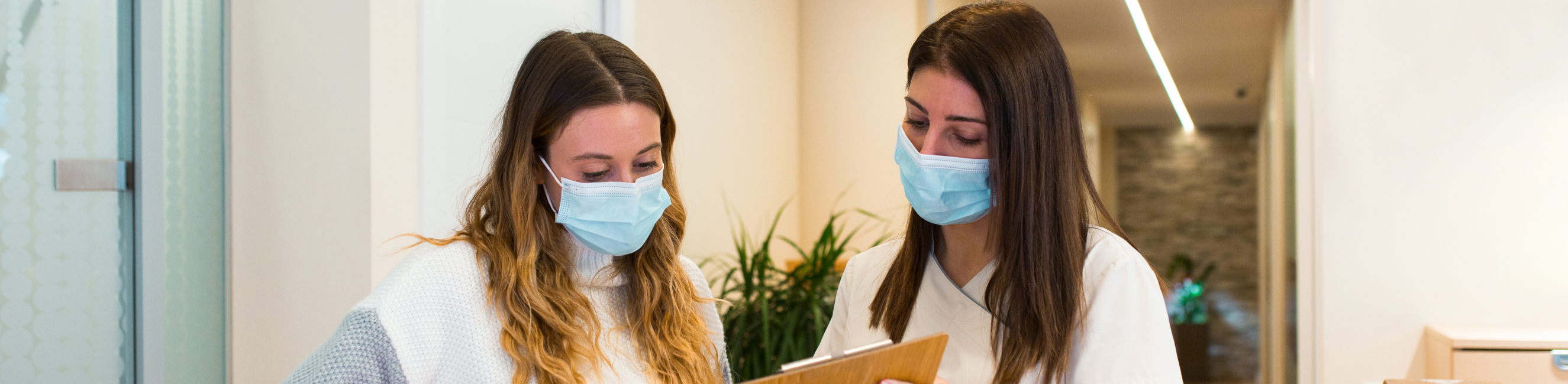 Two females working in a doctor surgery looking at a clipboard
