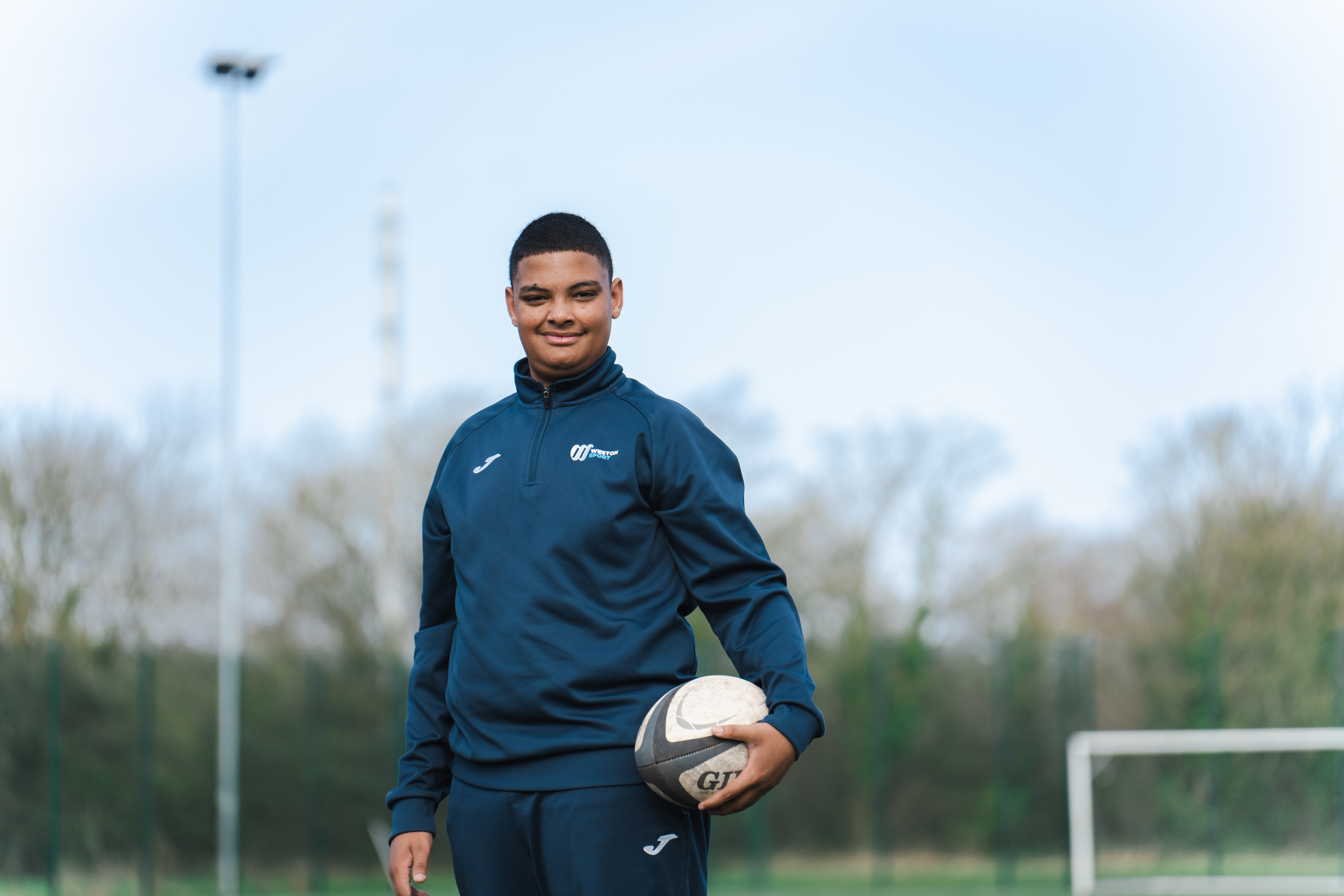 Student on the rugby field, holding a rugby ball