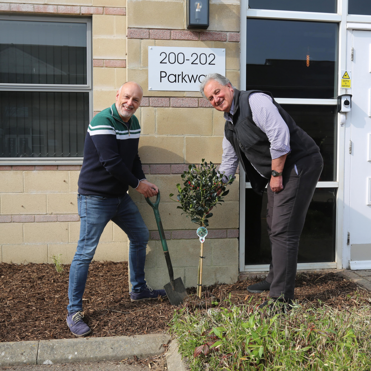 Ascot Group CEO Andrew Scott holding small freshly planted tree outside of Purplex Marketing building in weston-super-Mare next to weston college staff member Ian Porter