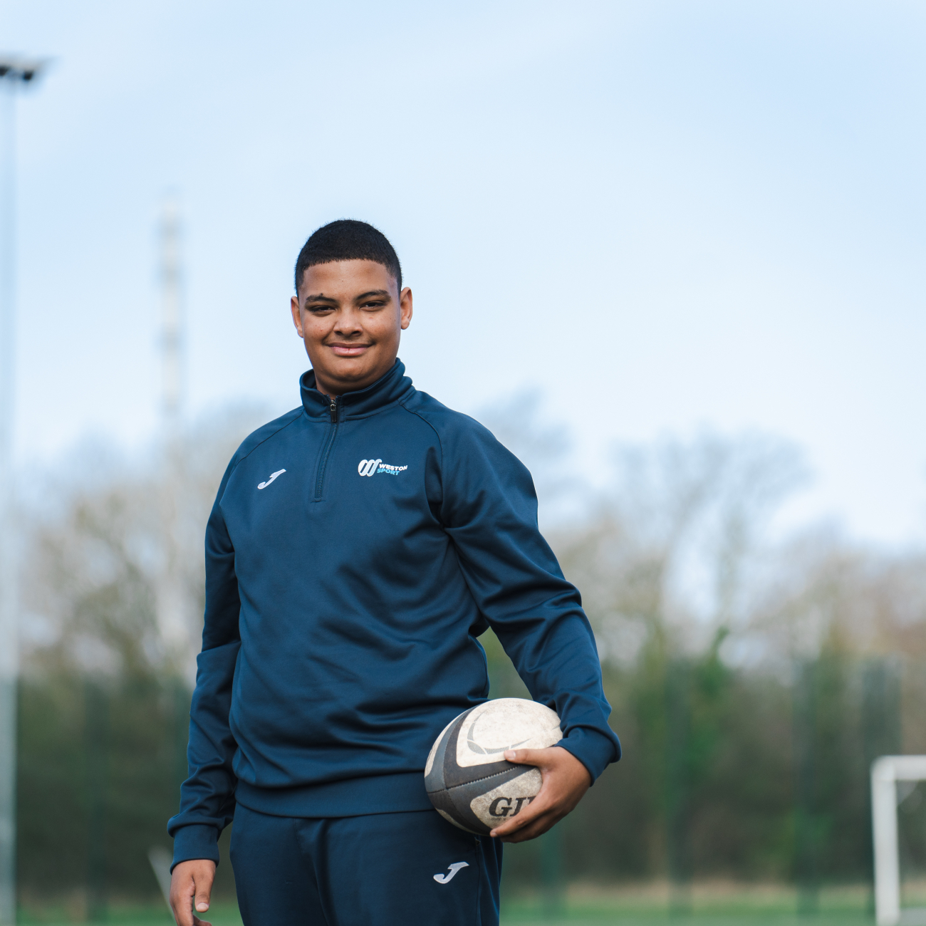 Student on the rugby field, holding a rugby ball