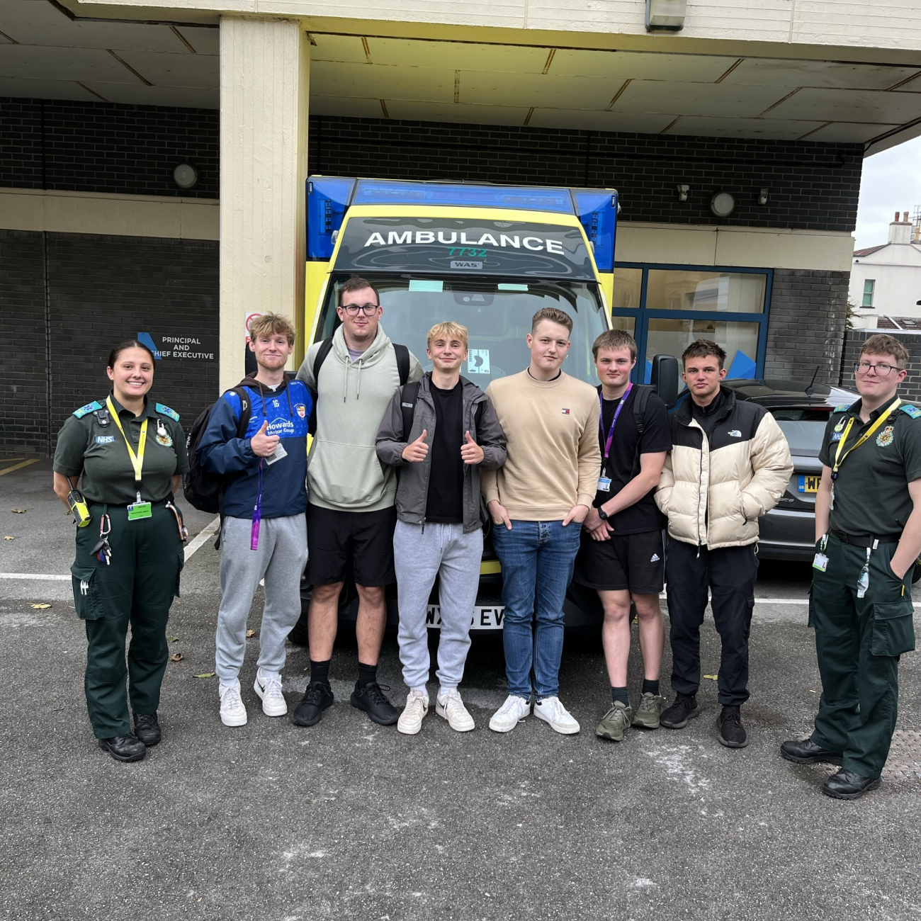 protective services students with former weston college students, now emergency care assistants, in front of ambulance