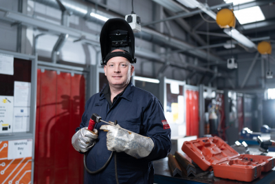 James with welding gear on holding a blow torch