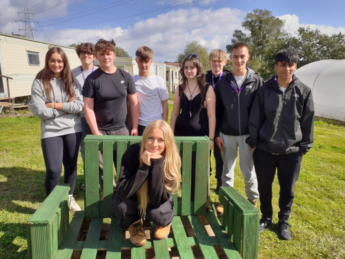 Learners smiling sat around the seat they built together