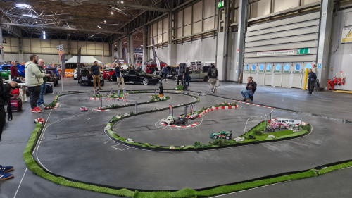 People playing with remote control cars around a mini racecourse