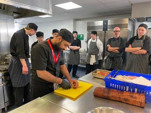 Syed cutting marinated chicken into pieces for the students to taste test