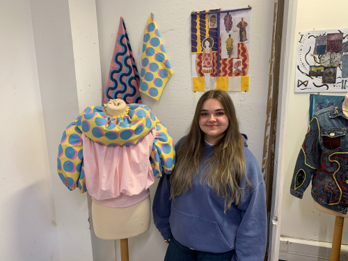 Molly standing next to her final project: a printed blouse