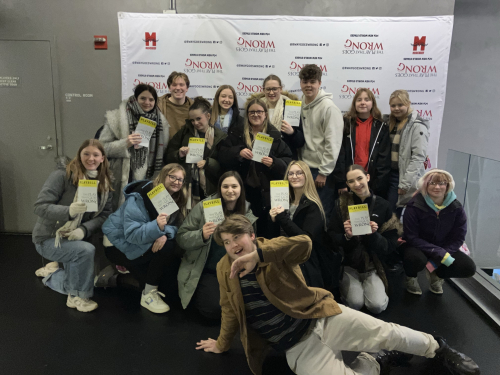 Students posing in front of the 'The Play That Goes Wrong' sign