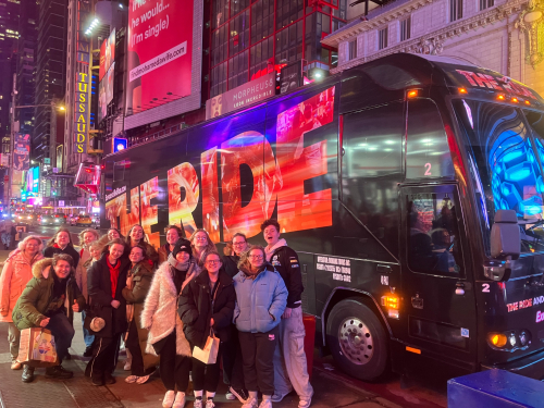 Students standing in front of 'The Ride' bus