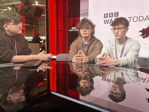 3 learners sat at the BBC Cardiff presenting desk