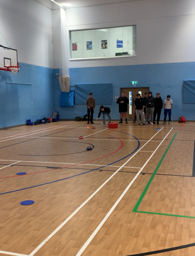 Sports coaching learners demonstrating curling in the sports hall