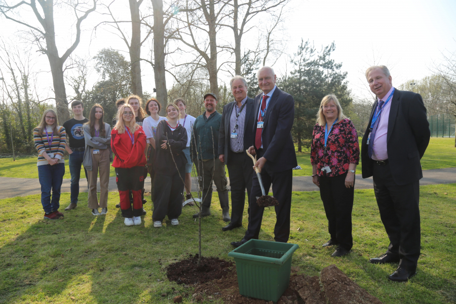 Creative arts students standing next to college principle, governors and staff planting an apple tree at Loxton campus