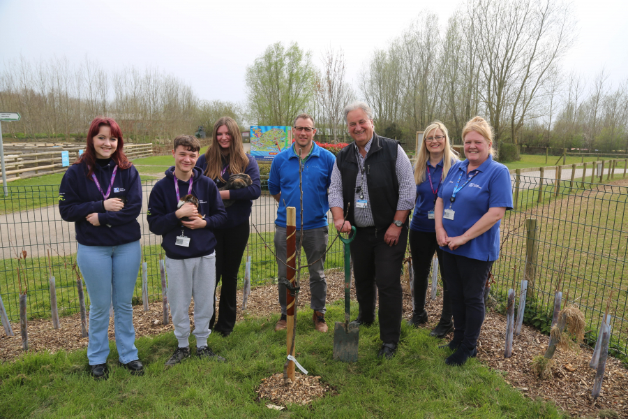 students holding rabbits and guinea pigs stood with members of staff planting a tree outside the weston college animal management education centre