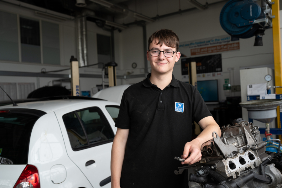 male motor vehicle student in front of car in workshop