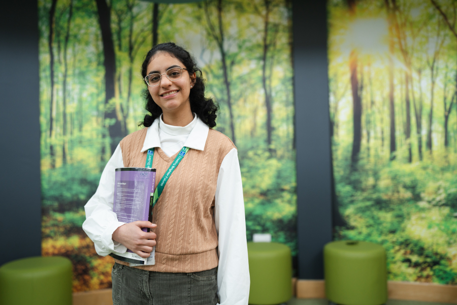 female student holding book in our LibraryPlus library