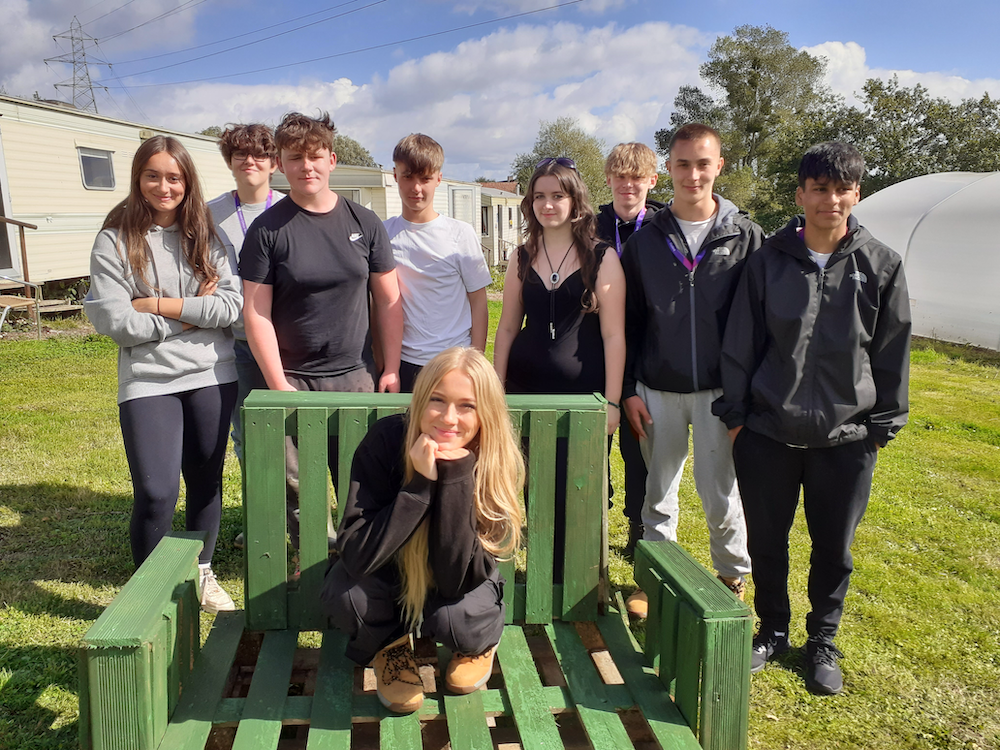 students standing with one student sitting on a chair in front of them